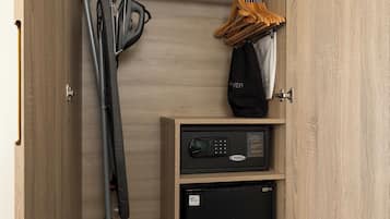 A compact storage unit with shelves, a small refrigerator, and a hanging rack for clothes.