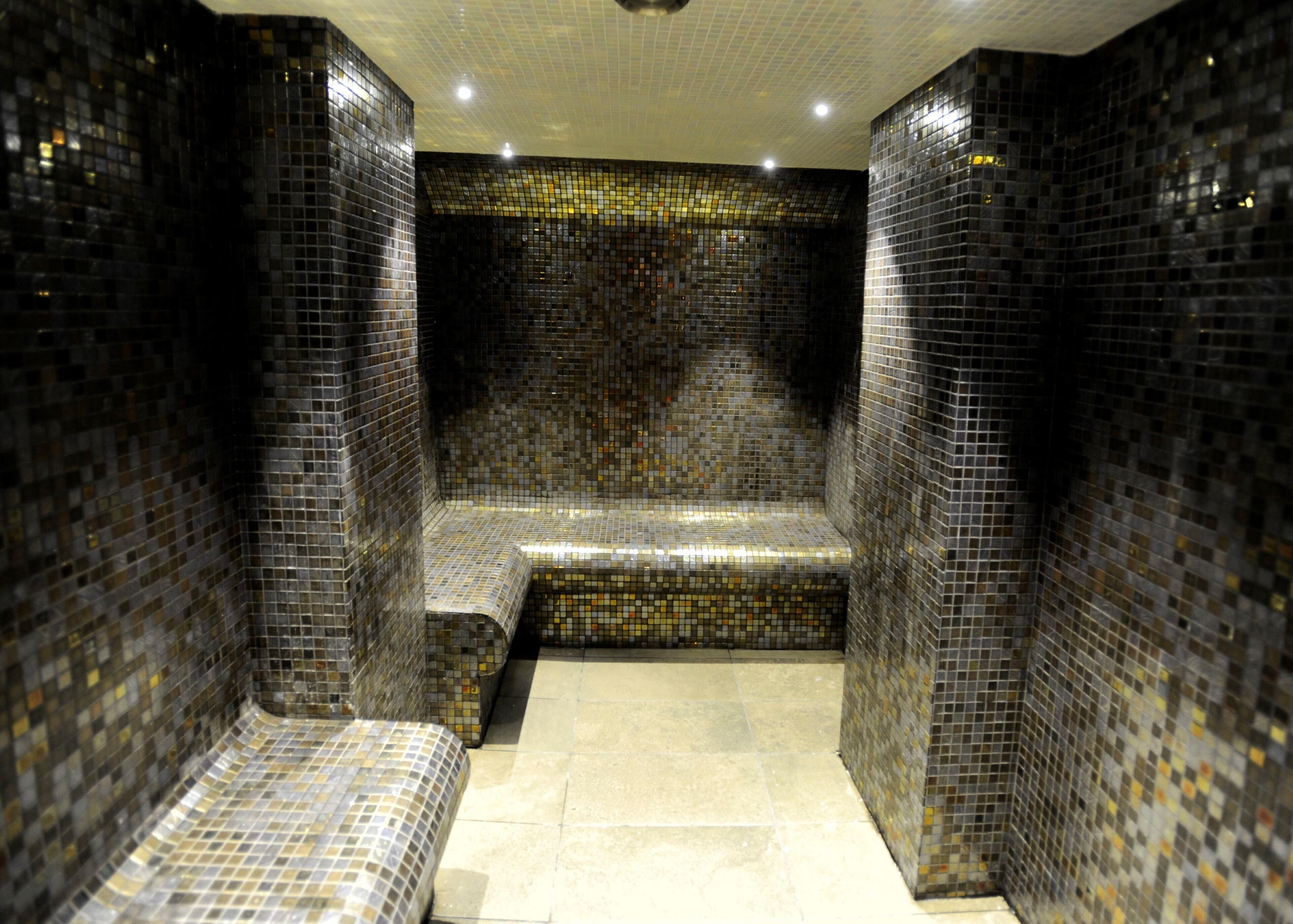 A tiled room with a bench and a tiled floor.
