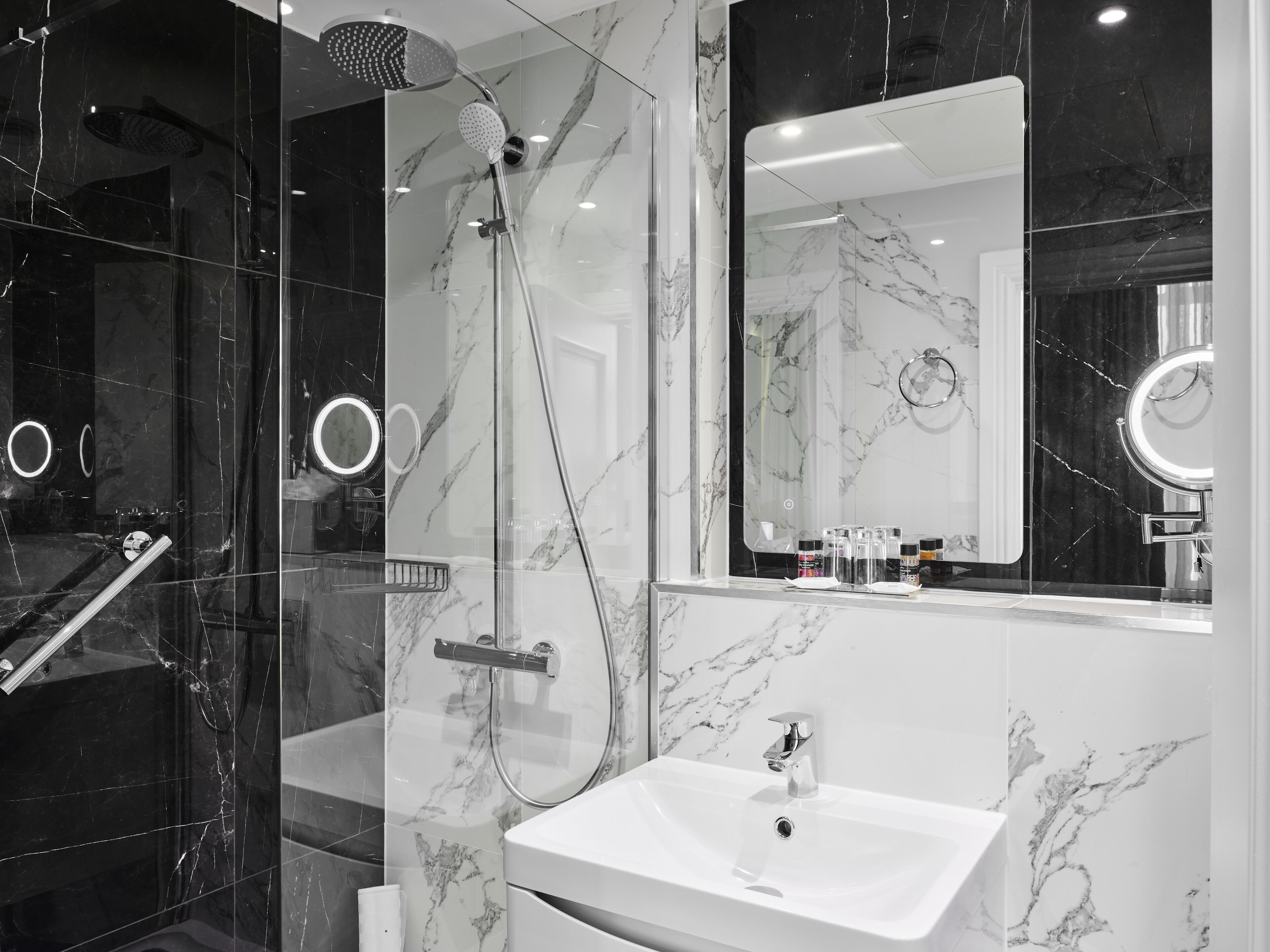 Une salle de bain moderne avec une douche à parois de verre, un lavabo blanc et un grand miroir.