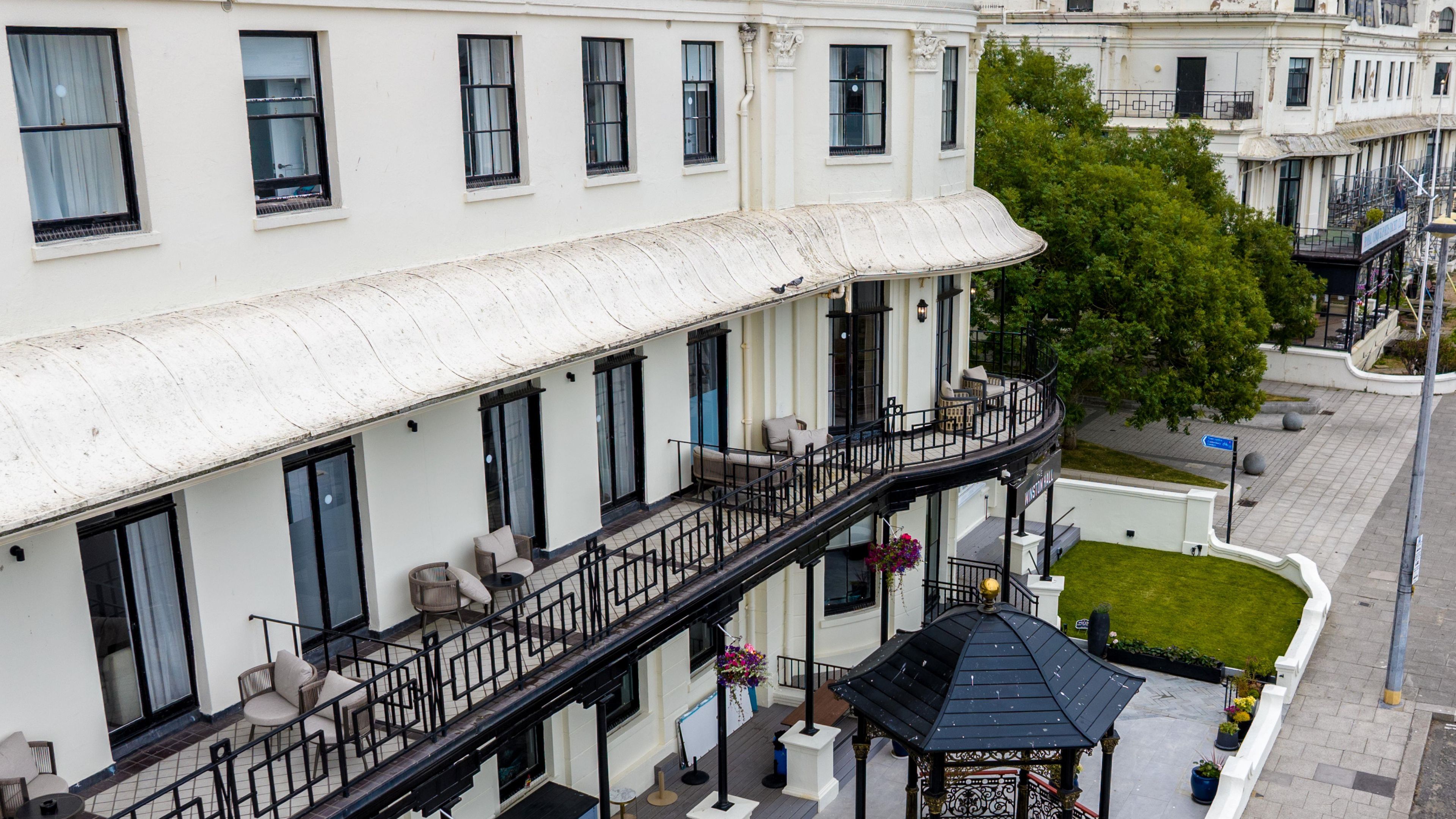 A multi-story building with balconies, outdoor seating, and a gazebo.