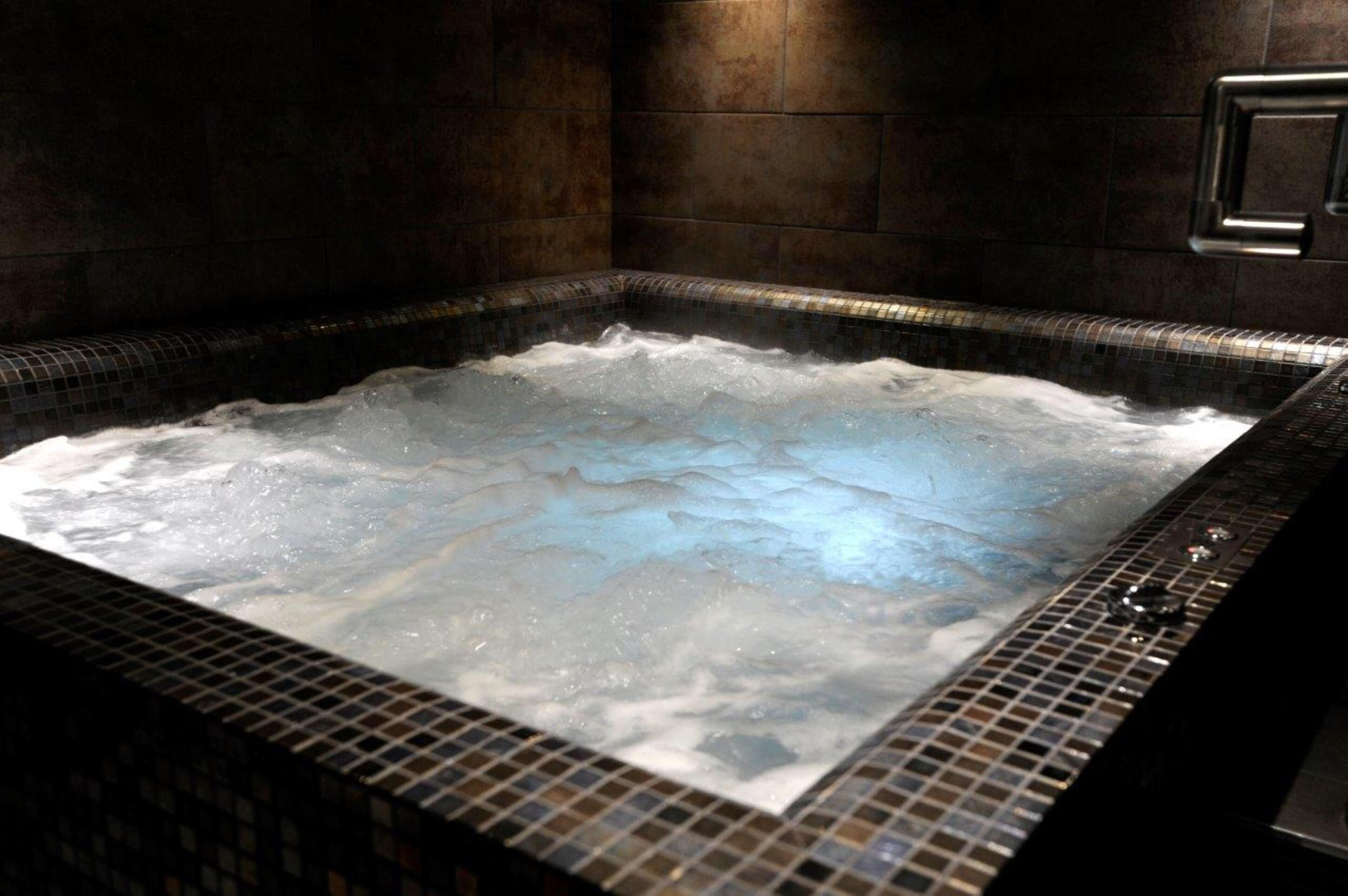 Un jacuzzi con revestimiento de azulejos y un panel de control a la derecha.