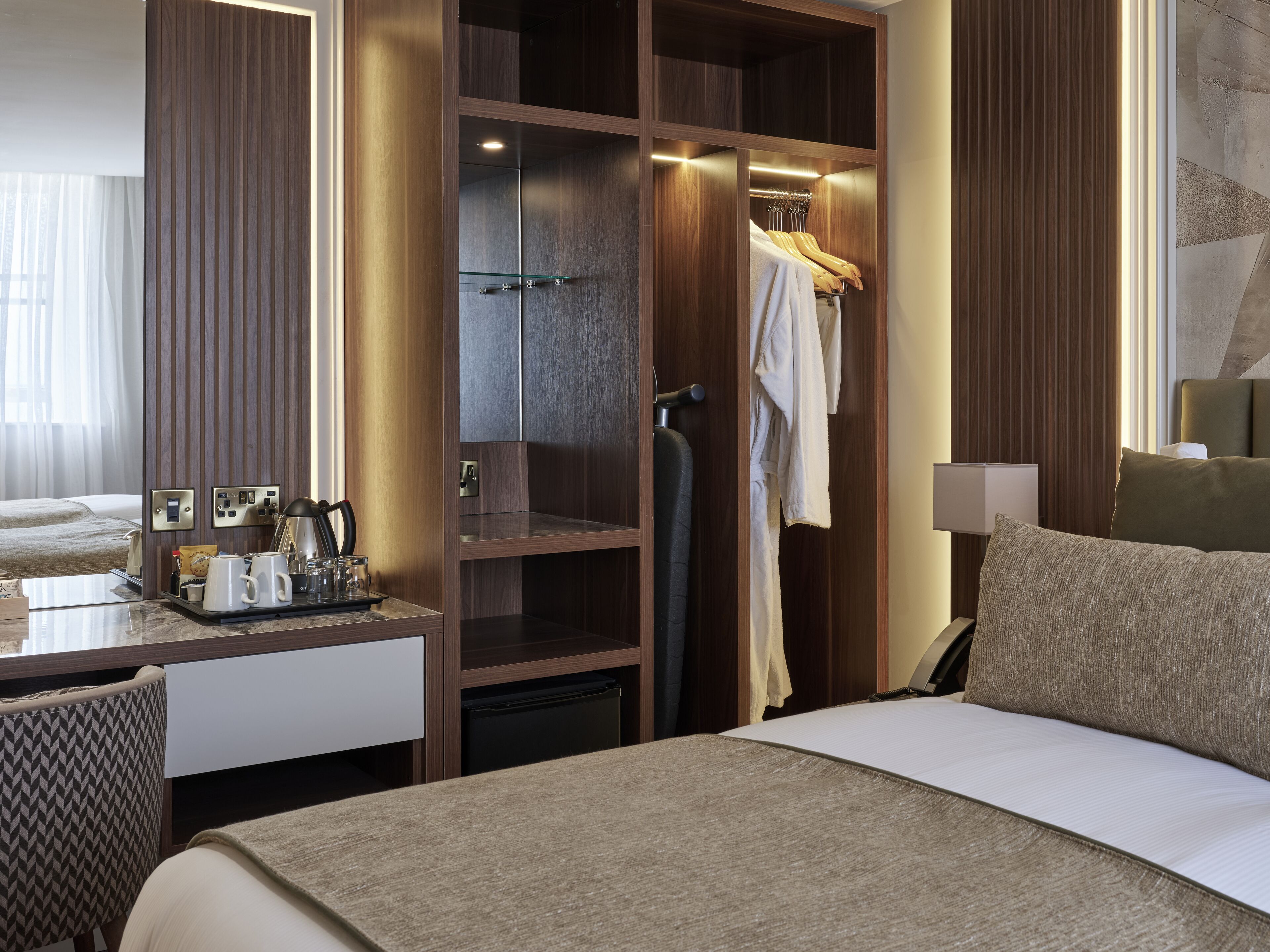 Ein Hotelzimmer mit Bett, Schreibtisch mit Kaffeemaschine, Kleiderschrank und Badezimmer mit Handtuchhalter.