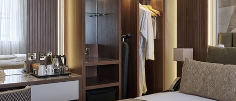 A hotel room with a bed, a desk with a coffee maker, a wardrobe, and a bathroom with a towel rack.