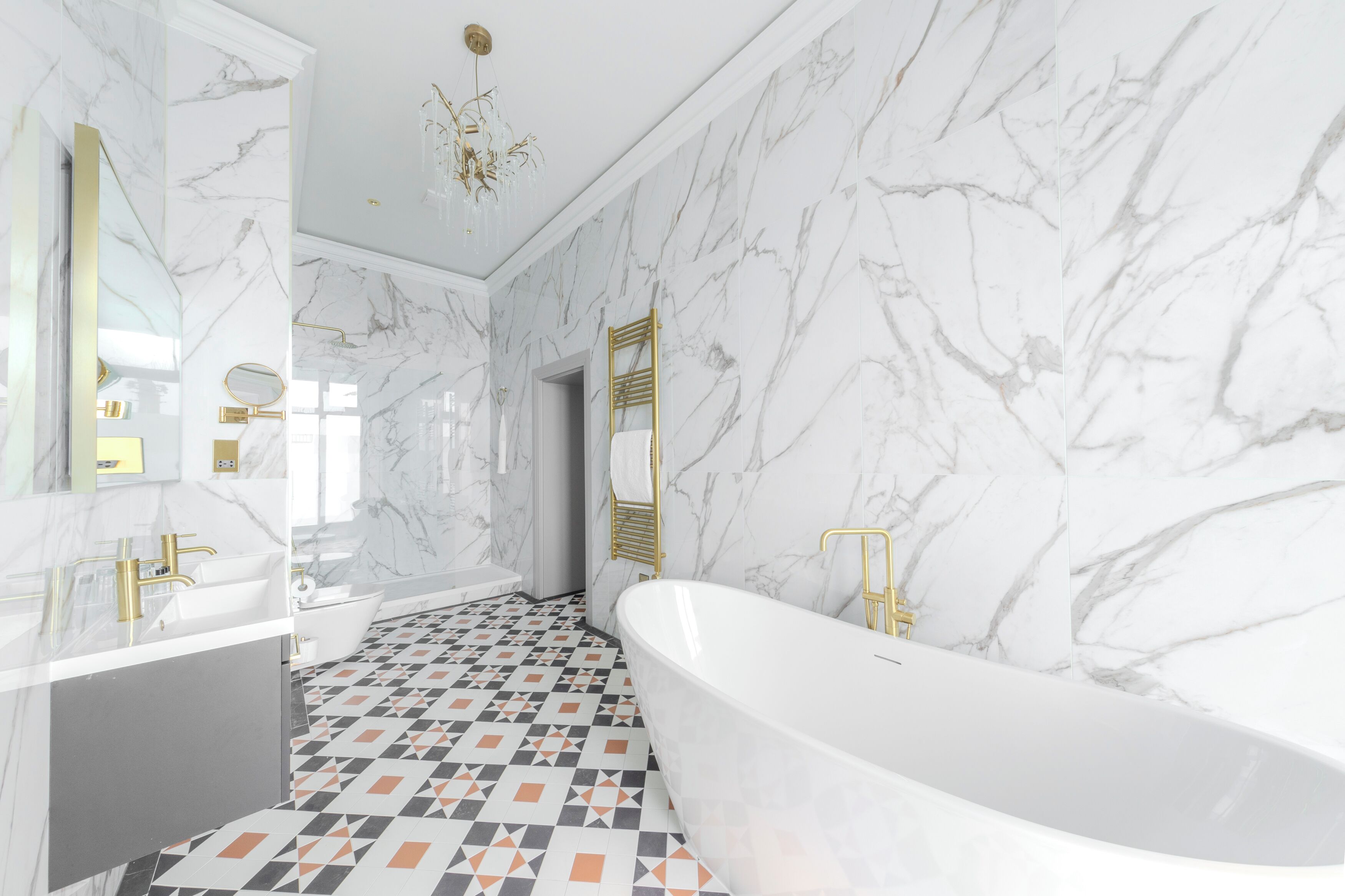 Une salle de bain moderne avec une baignoire sur pieds, un meuble-lavabo doté d’un robinet doré et des murs en marbre.
