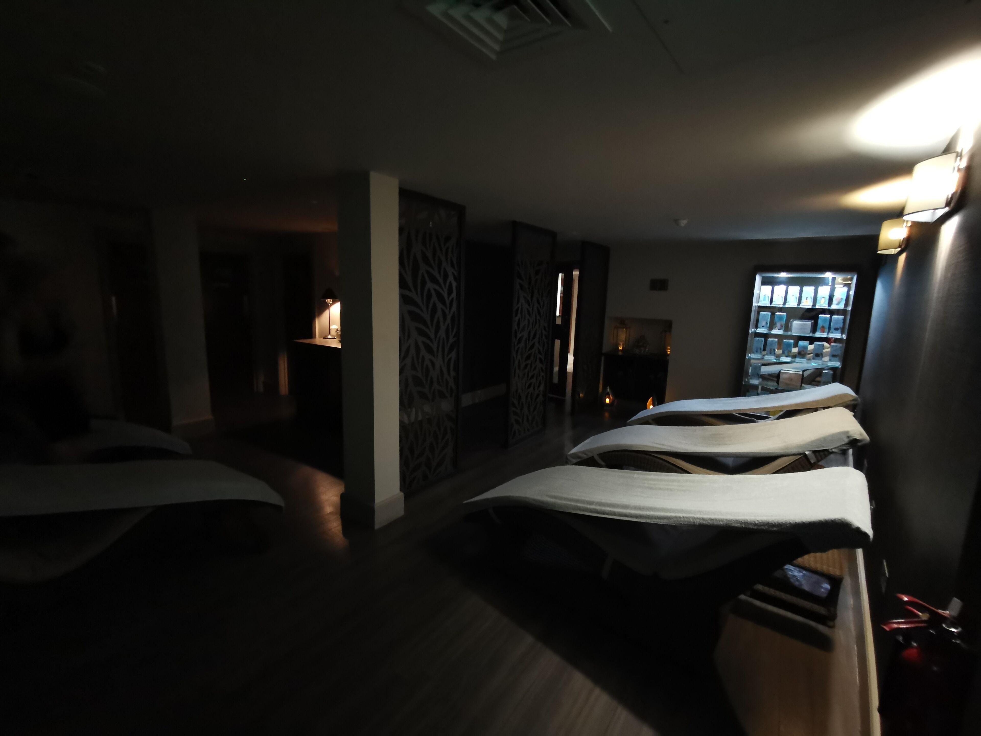 A dimly lit room with massage tables, a fireplace, and a display of framed pictures on the wall.