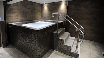 Relax in a spacious hot tub, surrounded by a mosaic-tiled bathroom with a metal staircase.