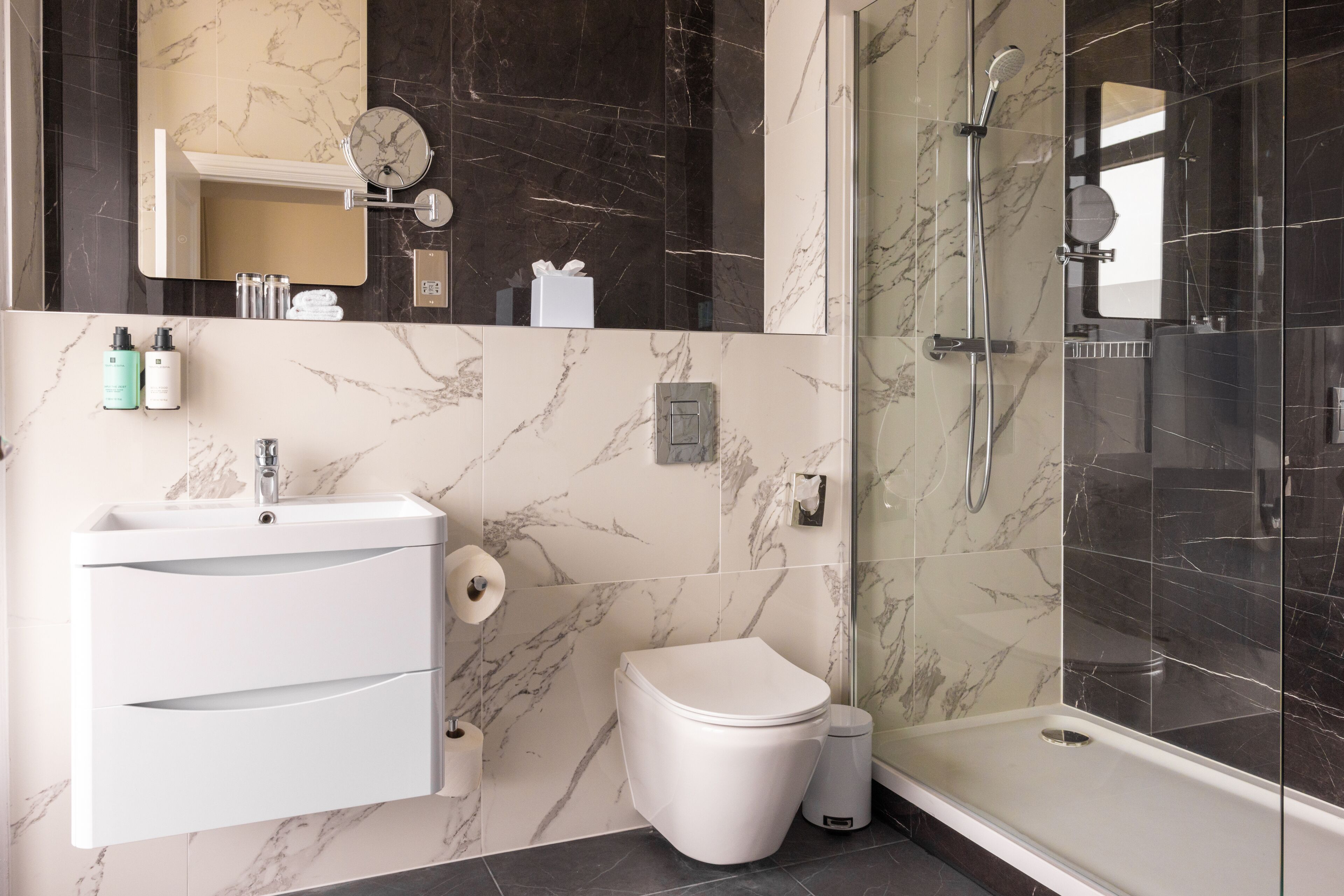 Une salle de bain moderne avec un lavabo, des toilettes et une douche en marbre.
