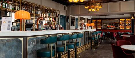 A bar area with a long counter, multiple stools, and a variety of bottles and glasses.