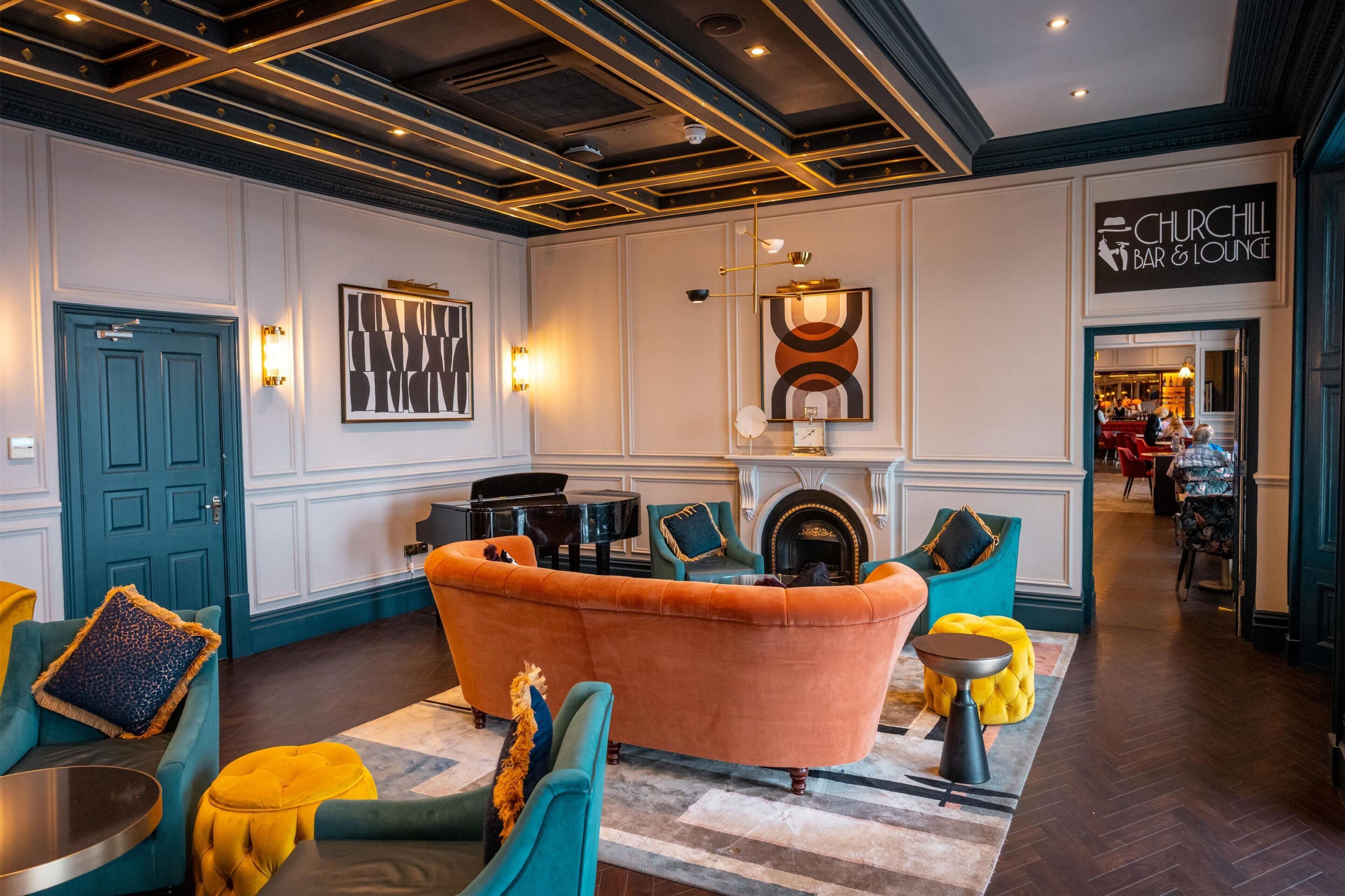 Un vestíbulo con chimenea, piano y zona de bar/salón.