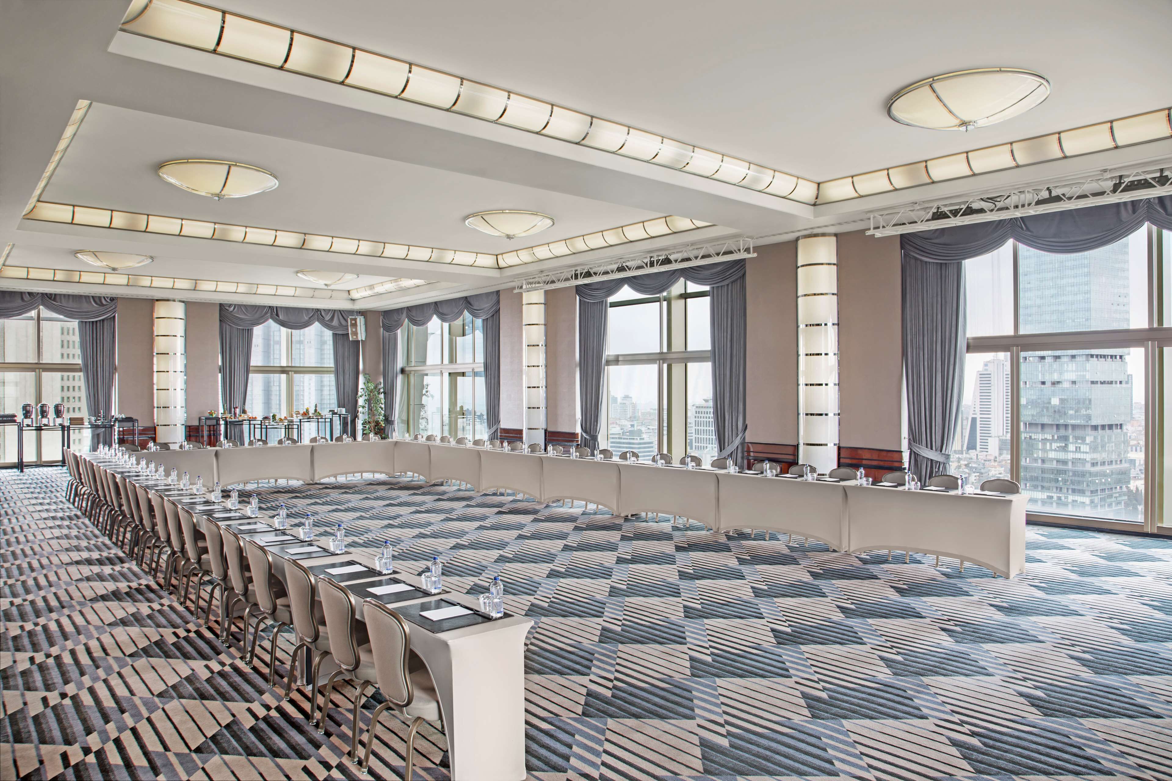 A large conference room with a long table, multiple chairs, and large windows offering city views.