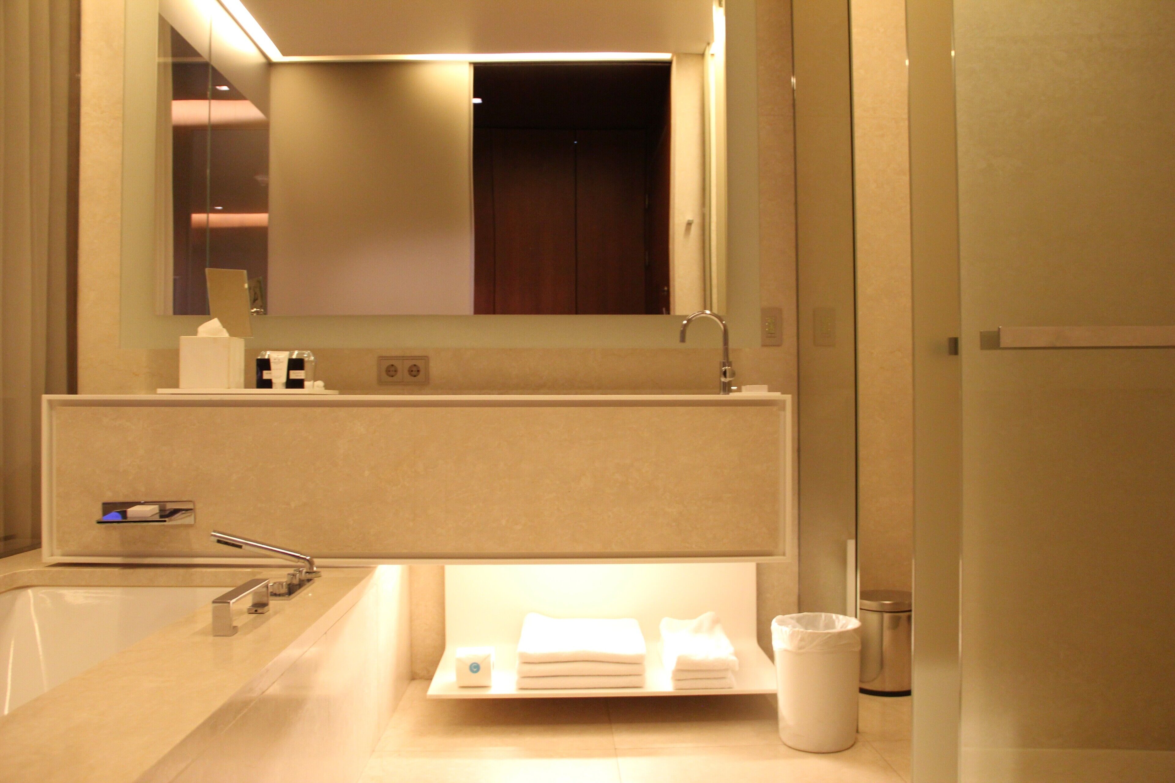 A modern bathroom with a large mirror, a sink, and a towel rack.
