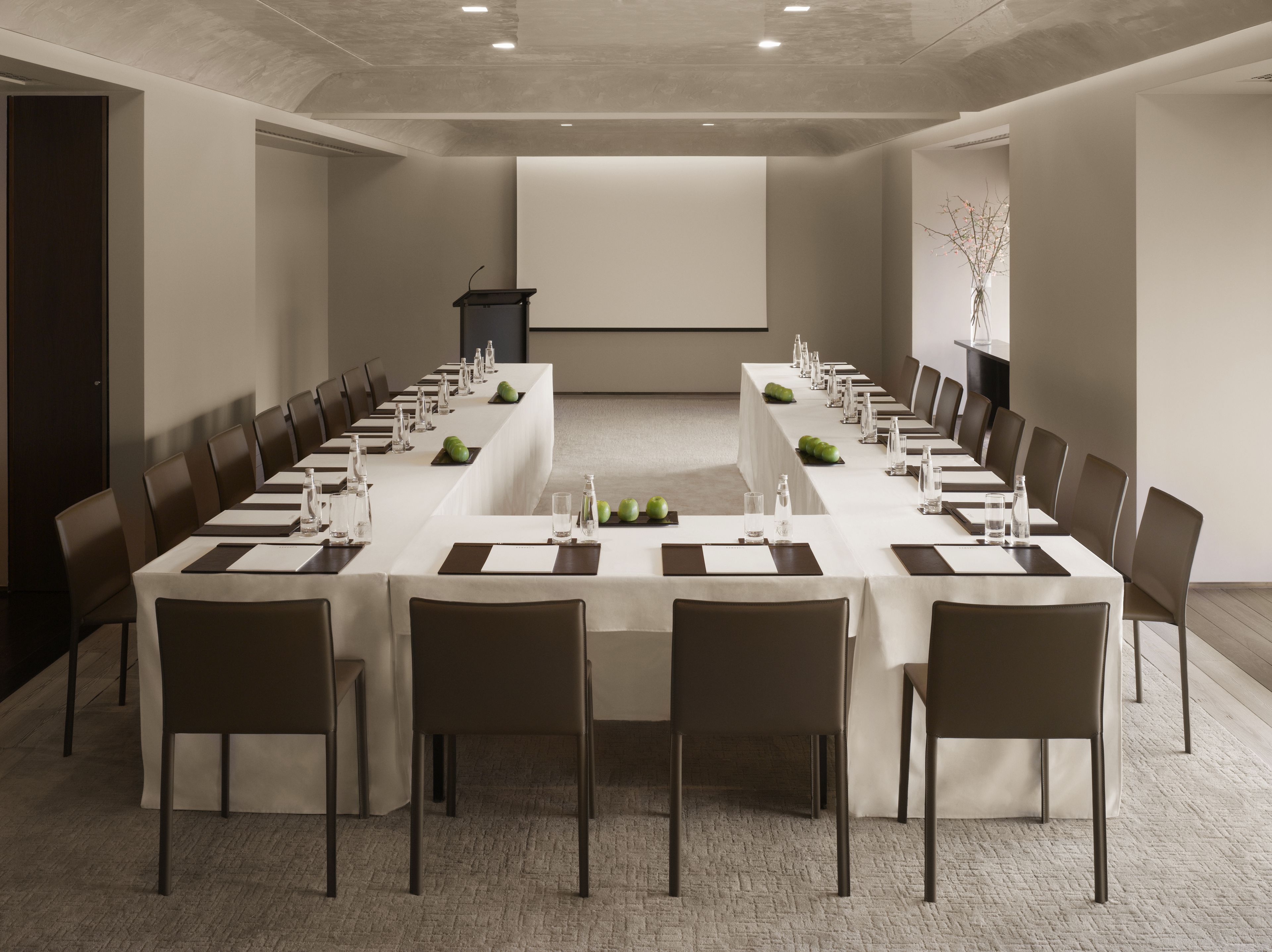 A conference room with a long table, chairs, and a podium.