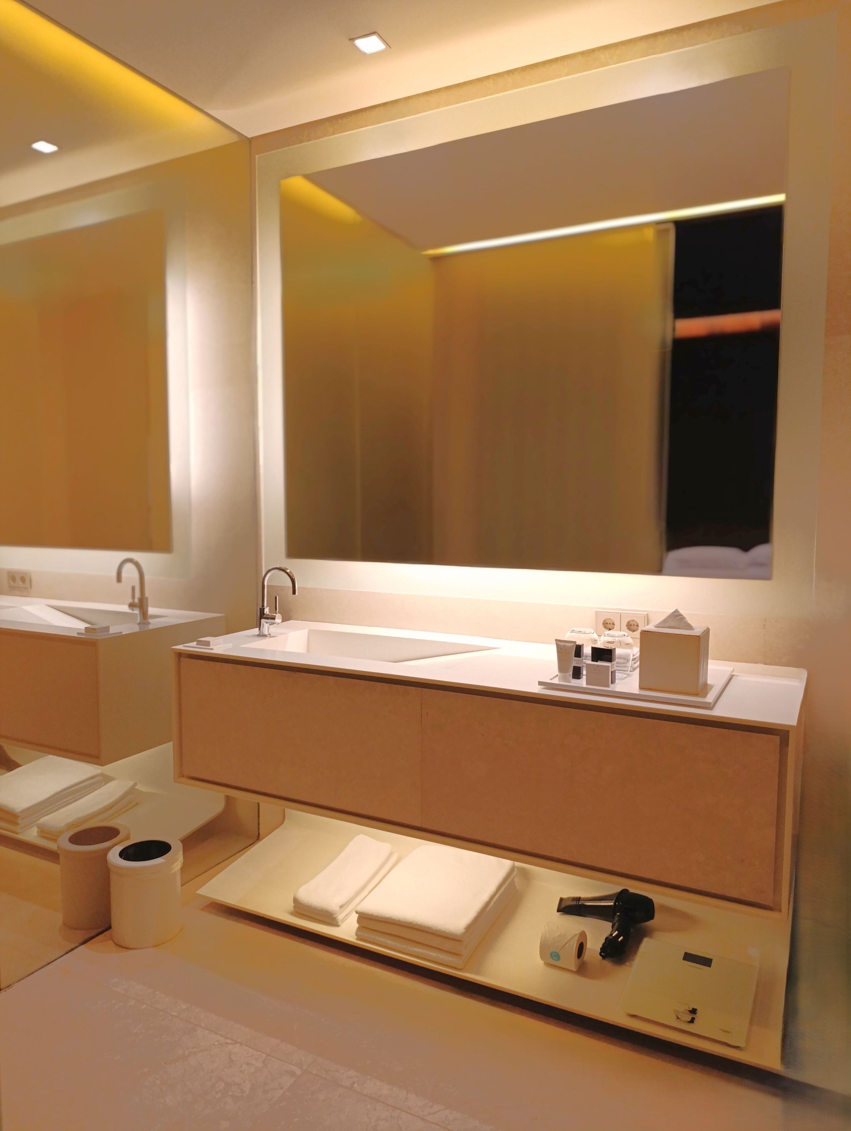 Un baño moderno con un espejo grande, un lavamanos y un mueble de tocador.