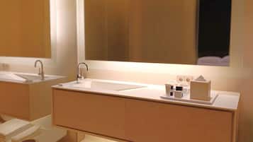 Un baño moderno con un espejo grande, un lavamanos y un mueble de tocador.