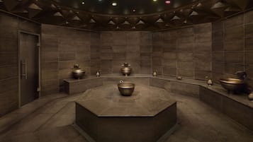 Un baño moderno con un lavabo hexagonal central, varios lavabos más pequeños y un diseño de techo geométrico y elegante.