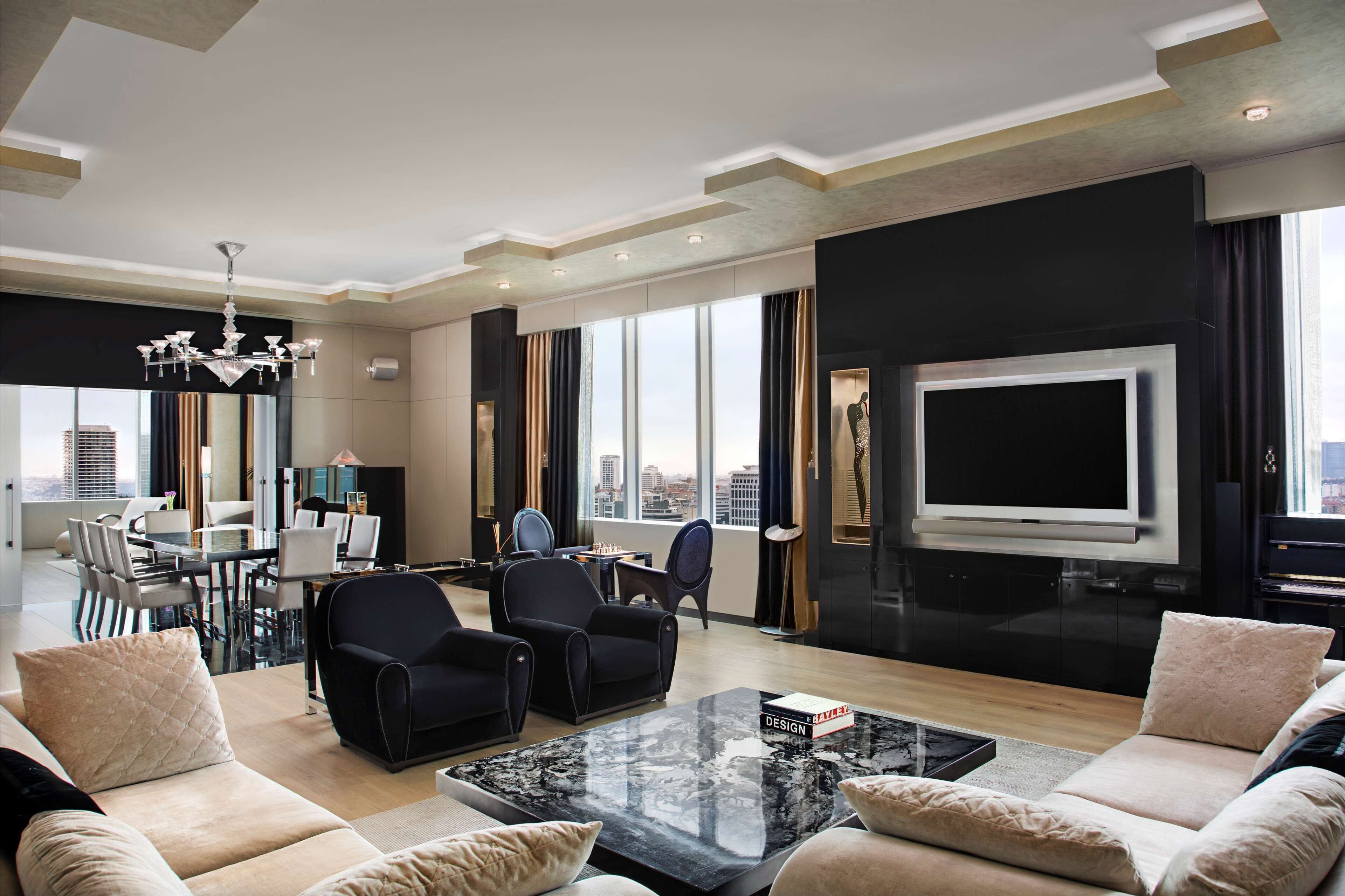 Uma sala de estar moderna com uma televisão grande, assentos confortáveis, um espaço de refeições e vista para a cidade.
