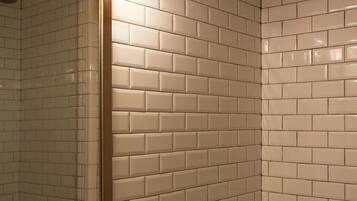 A bathroom with white subway tiles, a gold faucet, and a mirror with a gold frame.