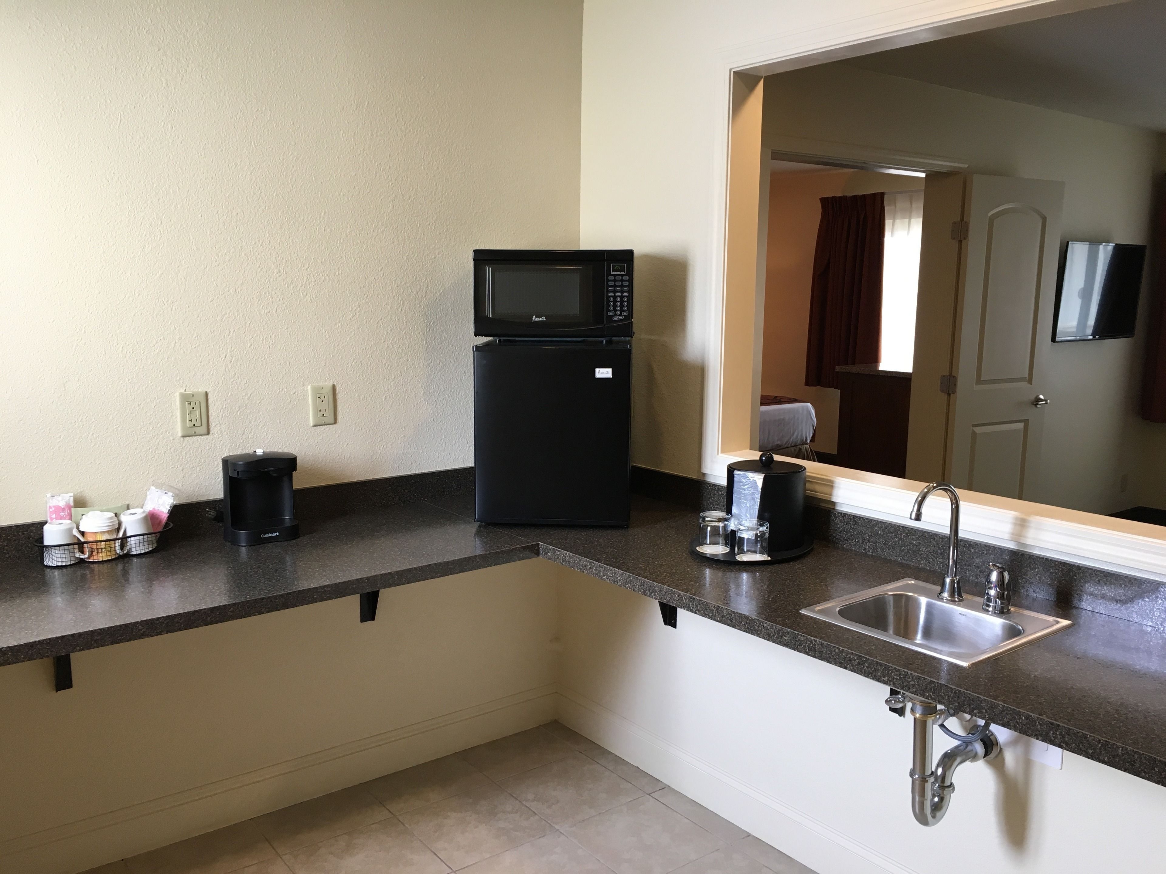 A kitchenette with a microwave, coffee maker, and a sink.