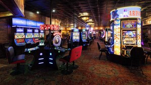 Ein Casino-Innenraum mit Spielautomaten, Roulette-Tischen und einer Bar.