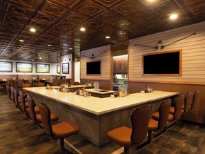 A bar area with a long counter, multiple seating options, and a decorative ceiling. - Ramada by Wyndham Elko Hotel at Stockmen's Casino (Elko)