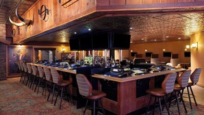 Eine Bar mit einer langen Theke, mehreren Barhocker und einem Wandgemälde.