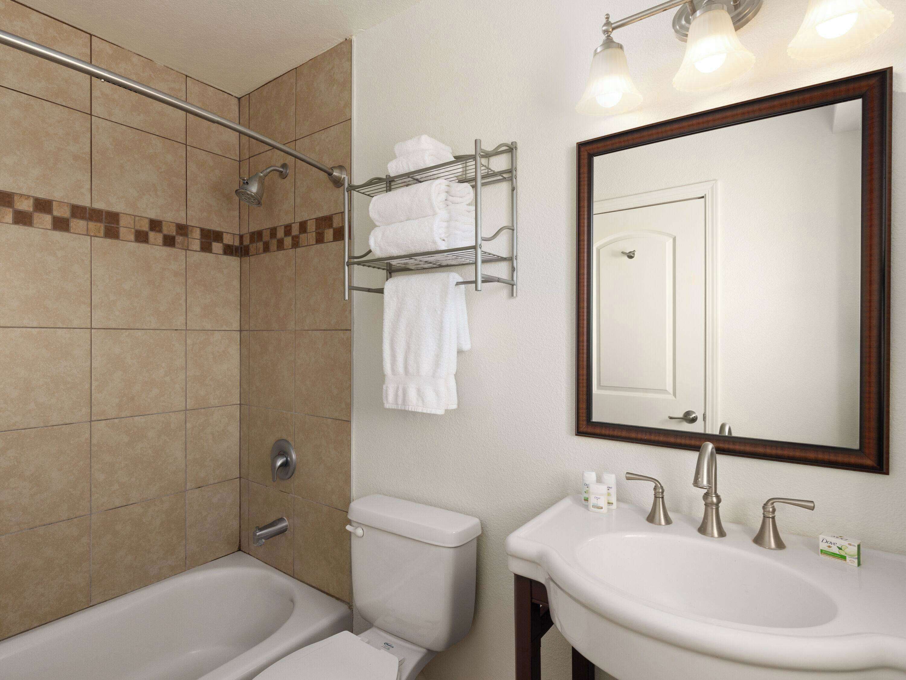 A bathroom with a bathtub, toilet, sink, and a towel rack with towels.