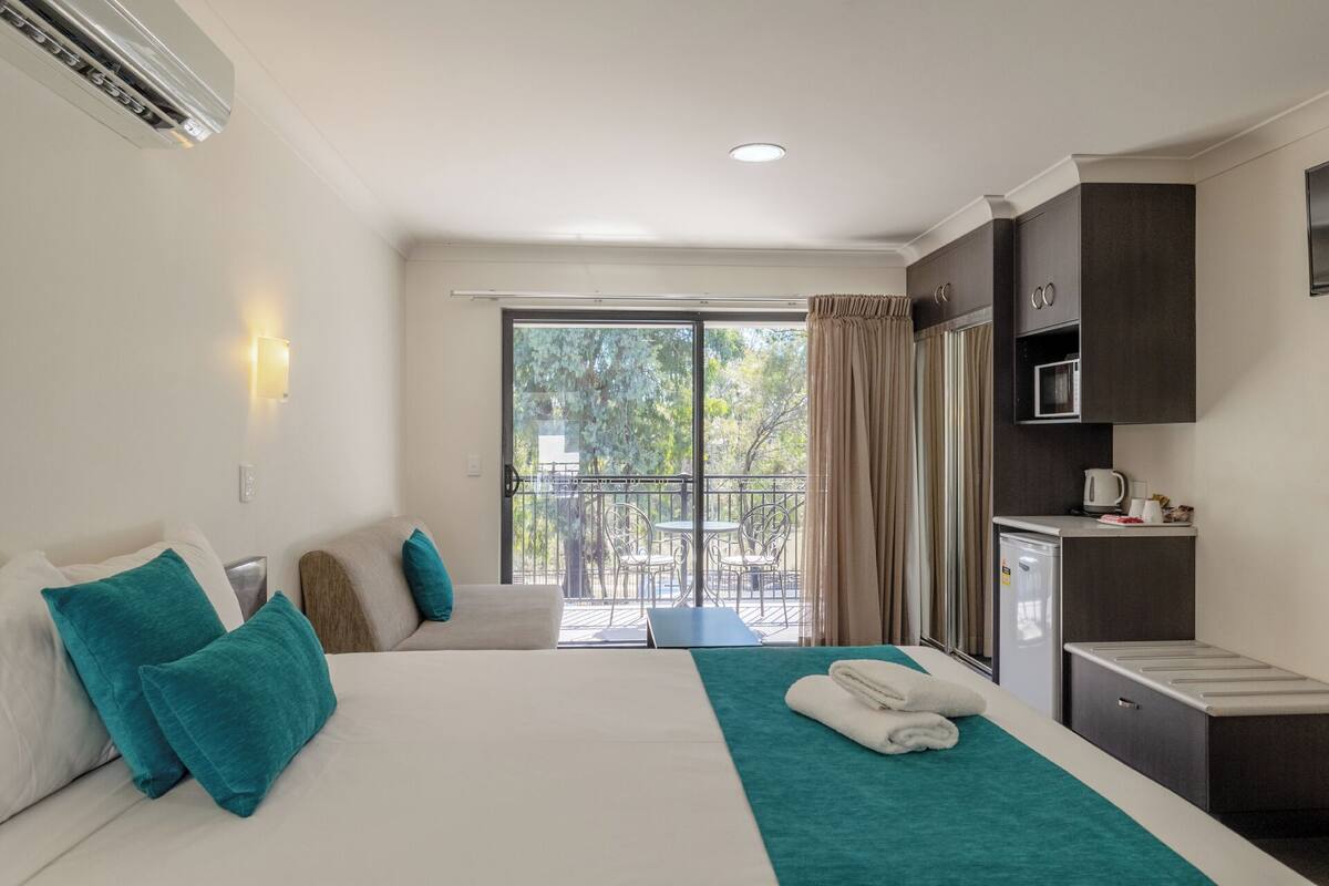 A hotel room with a bed, a desk, a microwave, and a view of the outdoors.