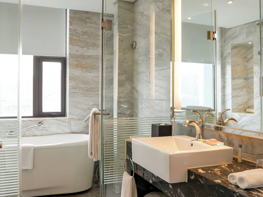 A modern bathroom with a glass-enclosed shower, a freestanding bathtub, and a large mirror.