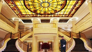 A grand lobby with a large stained glass ceiling, a central column, and a grand staircase. - Sunrise on the Bund (Shanghai)