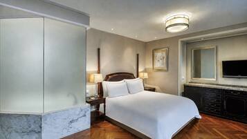 Een hotelkamer met een groot bed, een televisie, een marmeren accentmuur en een houten vloer.