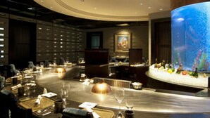 A modern dining area with a long table set for a meal, a large digital screen, and a decorative ice sculpture centerpiece. - Sunrise on the Bund (Shanghai)