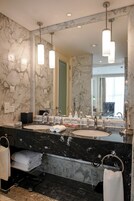 A bathroom with two sinks, marble walls, and a large mirror.