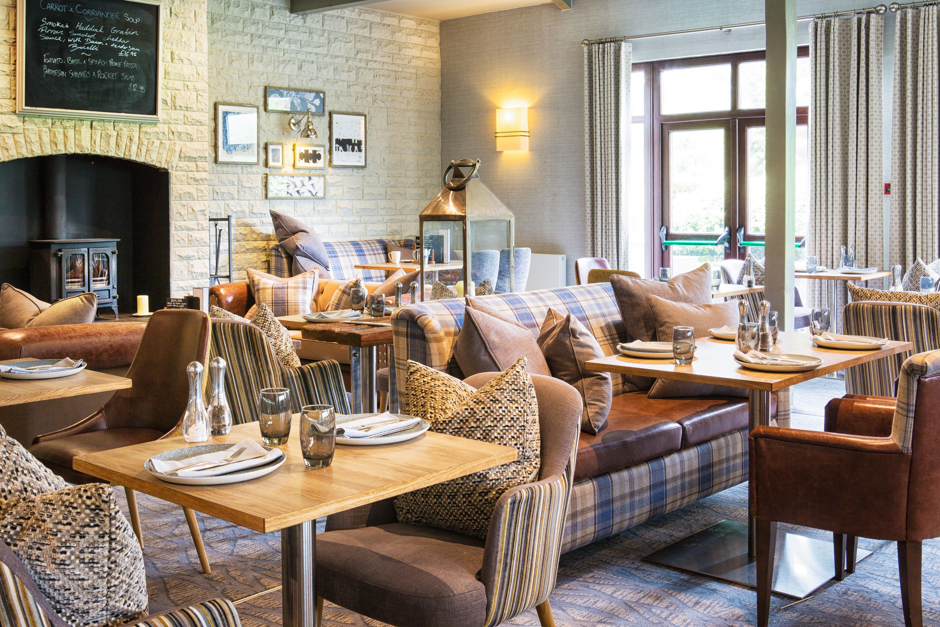 A cozy restaurant with a stone wall, wooden tables, and comfortable seating.