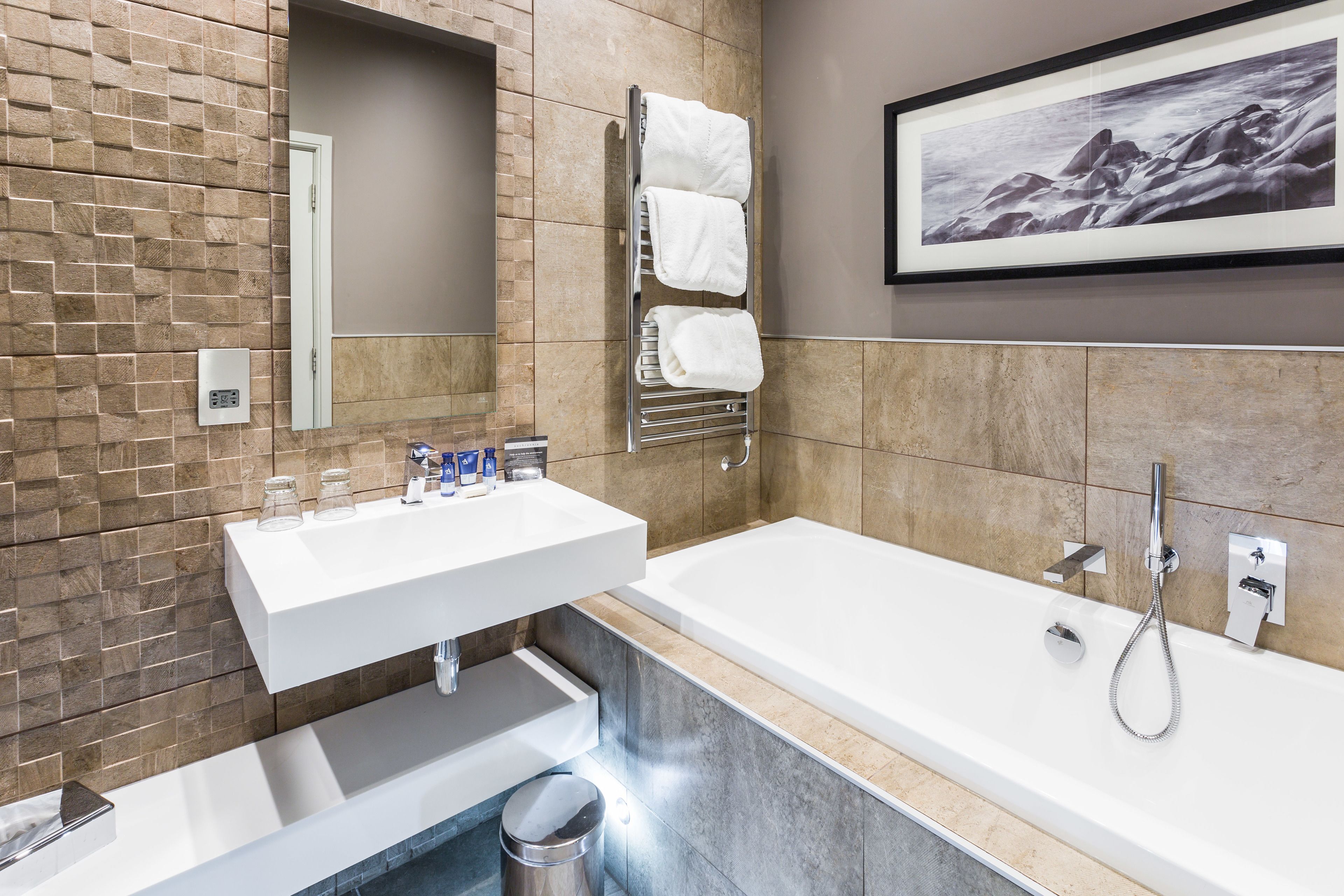 Un baño moderno con lavabo integrado, bañera y perchero.