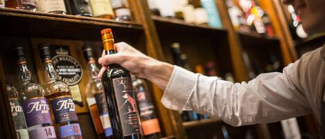 A person selecting a bottle from a shelf stocked with various liquor bottles.