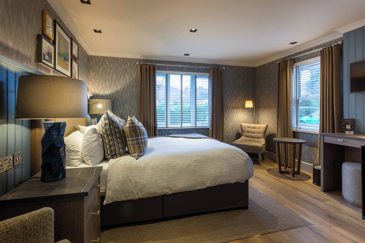 A hotel room with a large bed, bedside tables, a desk, and a TV.