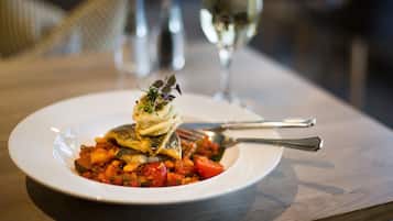 A plate of food with a fork and a glass of white wine on a table.
