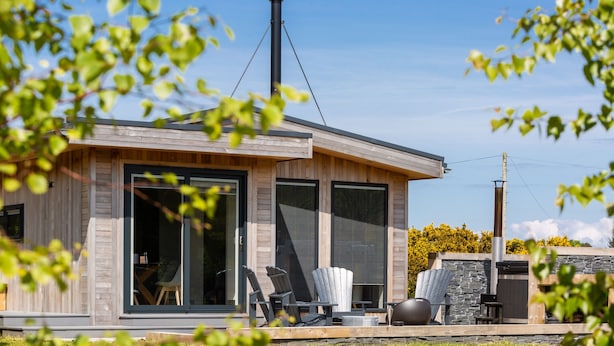 A modern house with large windows, a chimney, and outdoor seating.