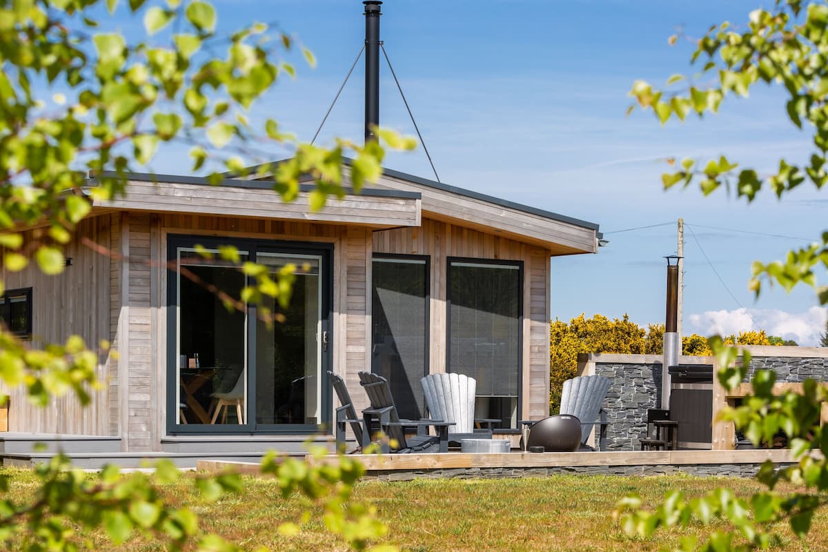 A modern house with large windows, a chimney, and outdoor seating.