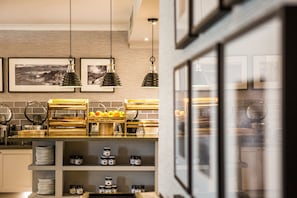 A modern kitchen with hanging pendant lights, a fruit display, and neatly organized shelves with plates and jars. - Auchrannie Resort (Isle of Arran)