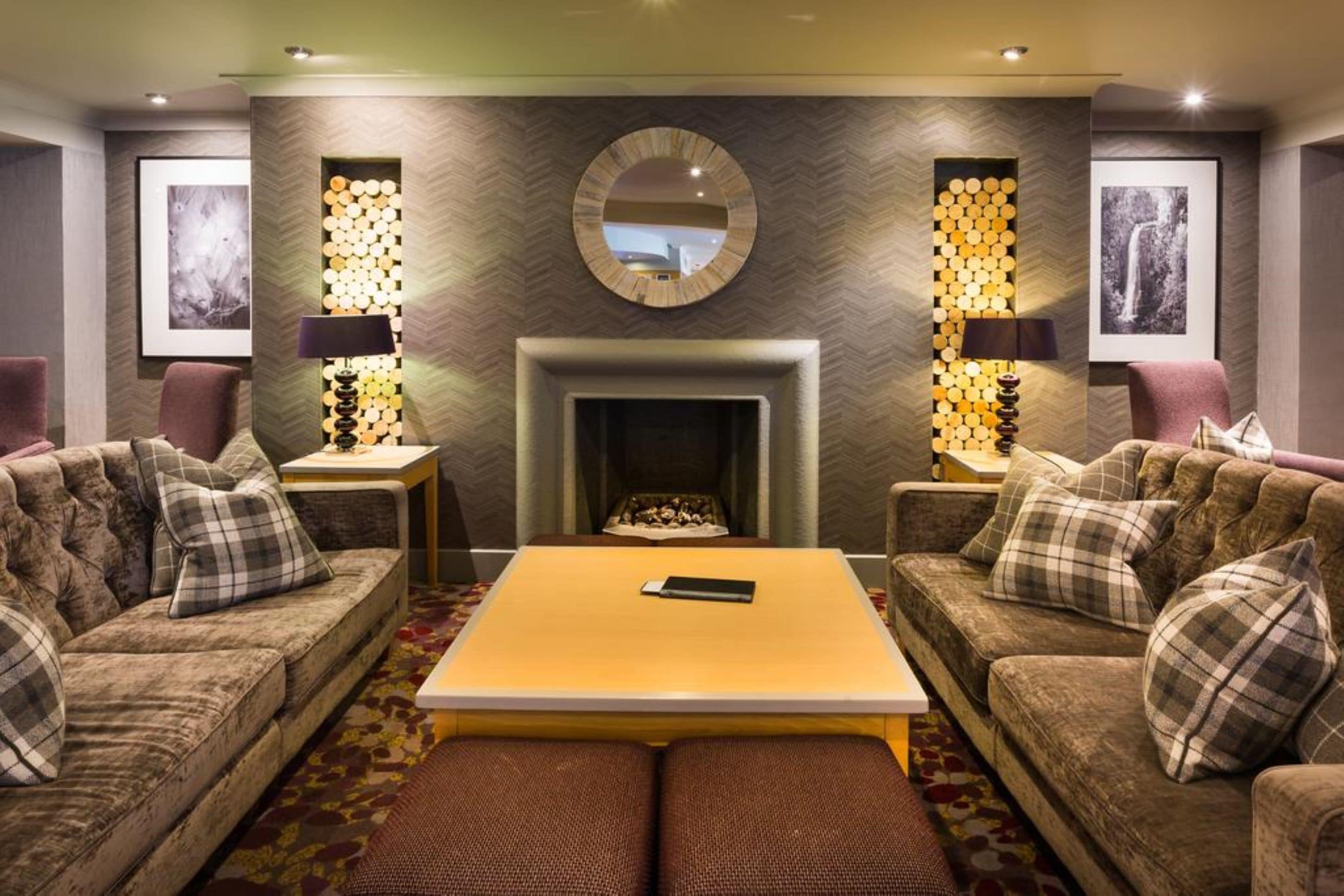 Un salon chaleureux avec deux canapés, une table basse, une cheminée et des panneaux décoratifs sur les murs.