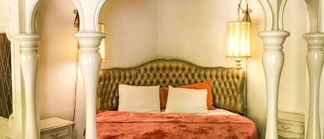 A room with a bed, a nightstand, a lamp, and a mirror.