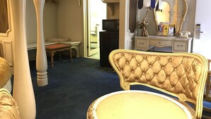 A room with a large bed, a vanity with a mirror, and a desk with a lamp. - Relax Inn Altoona (Altoona)