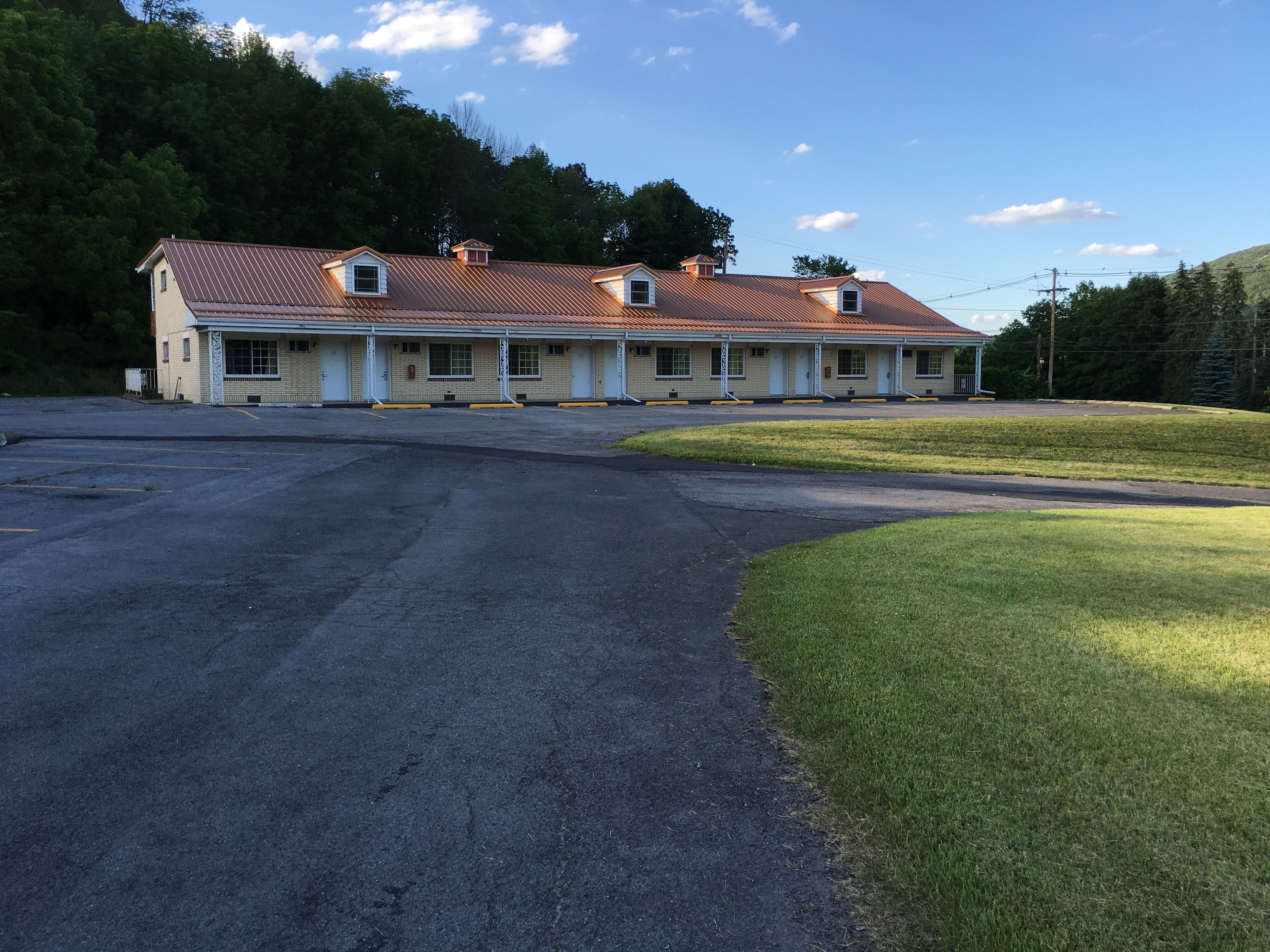 Un motel con una construcción larga de un solo nivel, múltiples ventanas y un estacionamiento.