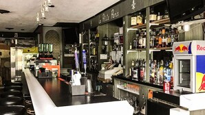 A bar with a counter, shelves with bottles, a Red Bull fridge, and a sign reading 'La Petite Paris'. - Relax Inn Altoona (Altoona)
