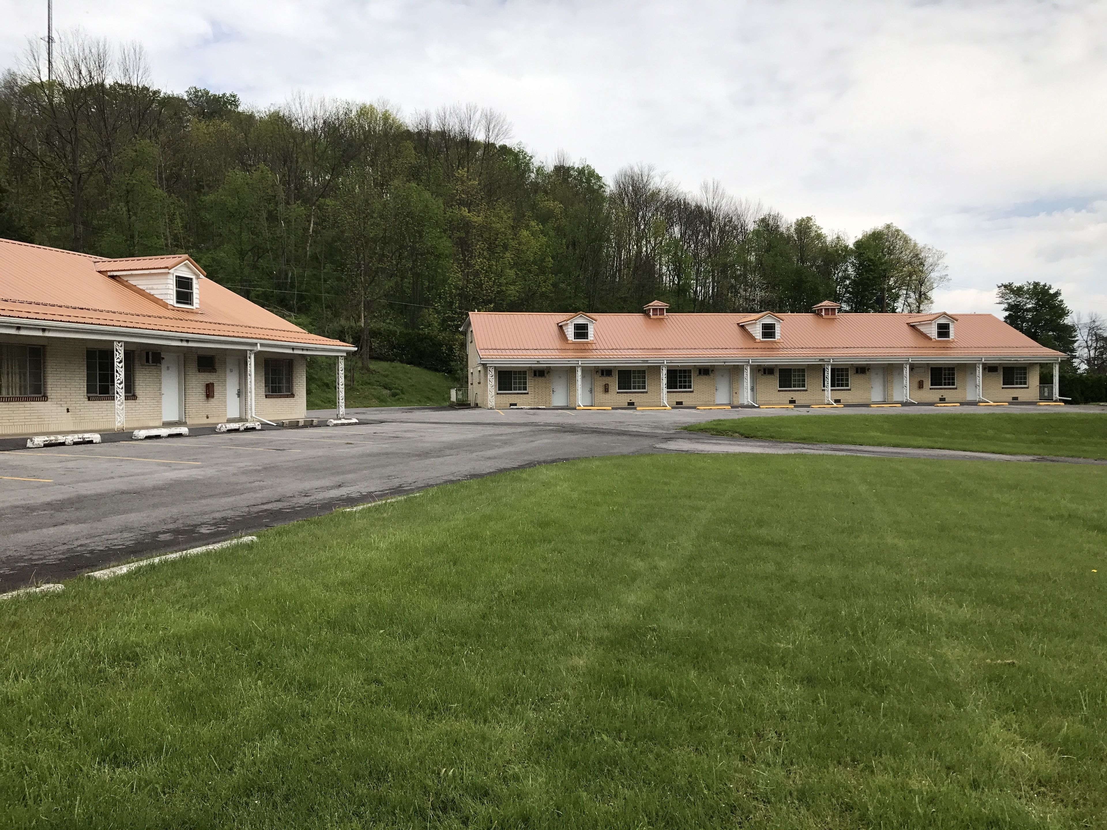 Een motel met een ruime parkeerplaats en een gazon ervoor.