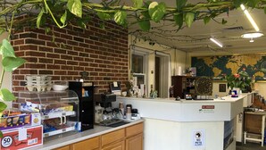 A coffee station with a brick wall, a coffee machine, and a counter with snacks. - Relax Inn Altoona (Altoona)