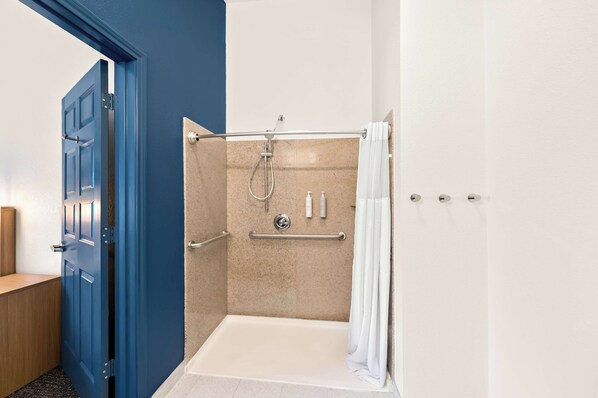 A walk-in shower with a beige tiled wall, a white shower curtain, and a door with a blue frame.