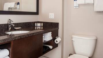A modern bathroom with a marble sink, a large mirror, a toilet, and neatly arranged towels.