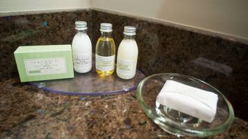 A bathroom counter with three bottles of body lotion and a box of bath soap.